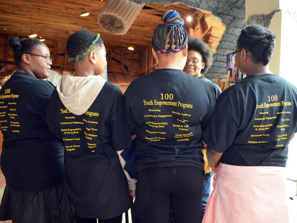 four students wearing black shirts with their backs facing the camera.
